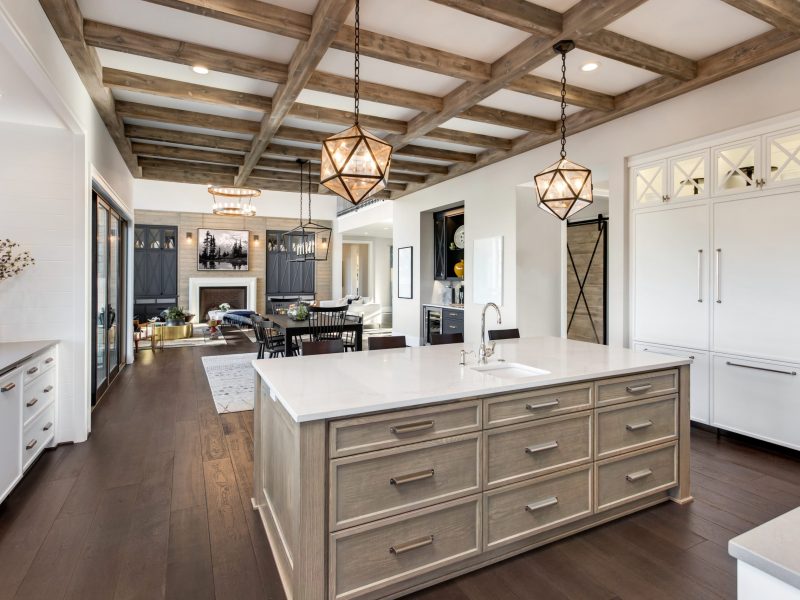 Beautiful open concept kitchen, dining room, and living room in new luxury home, with hardwood floors, fireplace, and dining table.